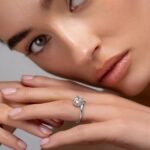 Сребърен пръстен с диамант, носен на ръката на жена с естествен грим.